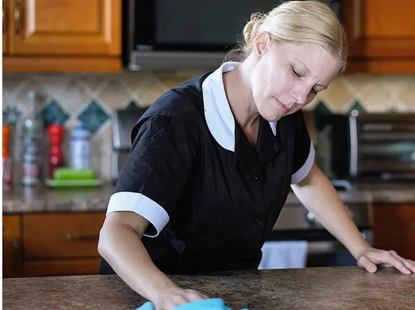Hearth & Home team member wiping a kitchen counter during a cleaning visit